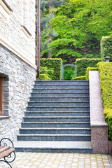 The steps of the granite staircase rise up along the wall of the beautiful estate and trimmed boxwood bushes. - 738861080