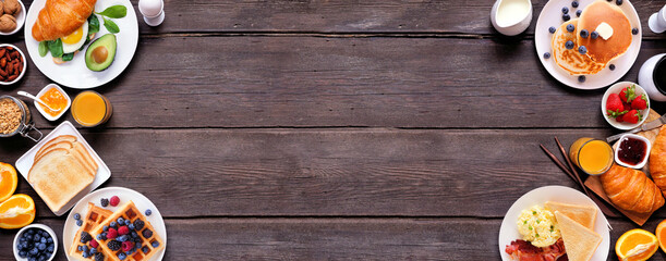 Breakfast or brunch double border on a dark wood banner background. Overhead view. Collection of sweet and savory food items.