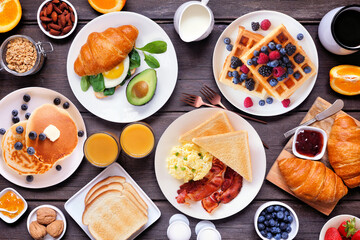 Breakfast or brunch table scene on a dark wood background. Overhead view. Variety of sweet and...