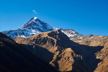 Majestic snow-capped peaks reaching for the sky, surrounded by the serene beauty of pure blue skies.