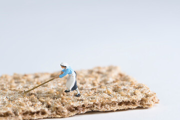 Photography of miniature people and toy figures, a farmer's wife working on a slice of crispbread