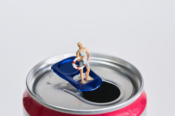 Photography of miniature people and toy figures, man in swimming trunks standing on a drinks can,