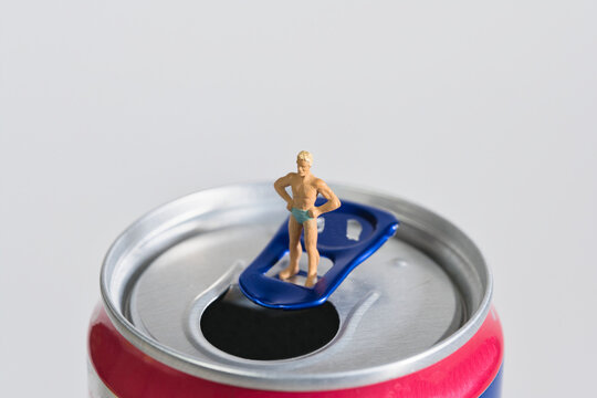 Photography of miniature people and toy figures, man in swimming trunks standing on a drinks can,