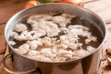 Removing the white foam know as chicken scum from the surface of stock pot when boiling chicken.