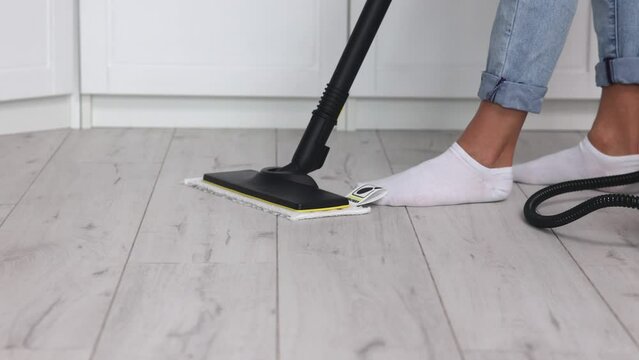 Removal of a used steam mop pad after a parquet floor wash by a worker in white socks and gloves. Professional Cleaning of the Apartment of a Cleaning Company