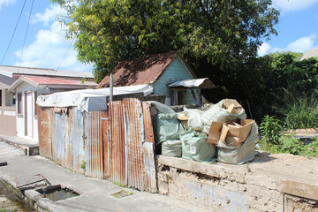 Rusted corrugated fence and trash in front of an abandoned home in St. John's Antigua