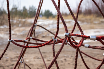 Red rope sections fastened with a metal clamp and a brown sand background
