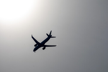 
black and white picture with a silhouette of an airplane in a gray sky