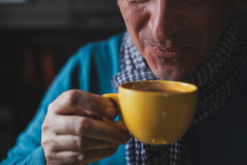 Adult mature man drinking tea and looking outside the windows at home