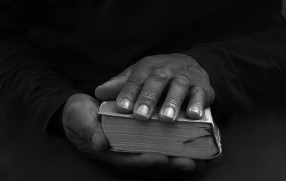 man praying with bible with black background with people stock image stock photo	