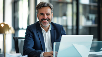 Smiling mature adult business man executive sitting at desk using laptop. Happy busy professional mid aged businessman ceo manager working on computer corporate technology in office