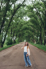 A young girl, a woman walks through a tunnel of green trees. Warm summer day. The girl is dressed lightly.