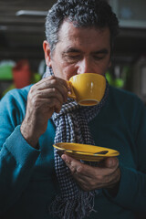 Adult mature man drinking tea and looking outside the windows at home