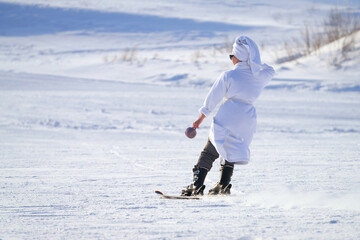 Ski season. Mock downhill skiing on a snowy track of a girl in a banana robe with a towel on her...