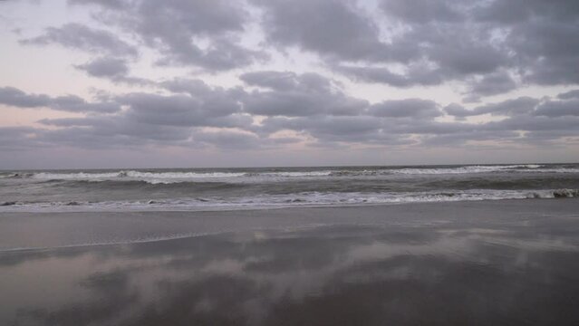Vacations. Panorama view of the empty beach and ocean under a sunset sky. Beautiful sky reflection in the sea waves.