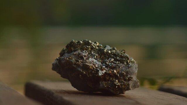Close-up, pyrite crystal lies on a wooden pier against the background of the river 