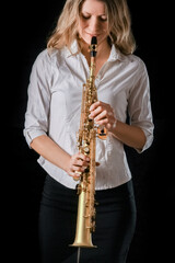 soprano saxophone in the hands of a girl on a black background