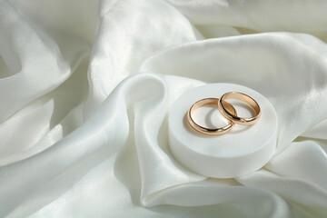 wedding background. gold wedding rings on white satin fabric. marriage is a concept. copy space.