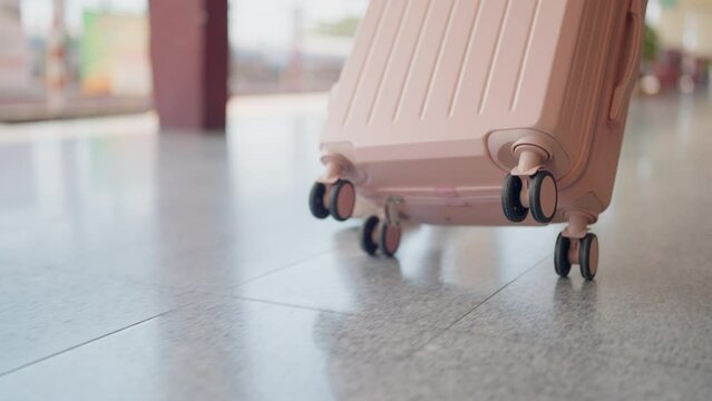 A person, likely a woman, is seen walking with a rolling suitcase at a travel terminal, signifying a journey.