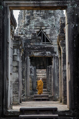 A monk coming to the ancient Hindu temple of Angkor Wat in Cambodia, Asia.