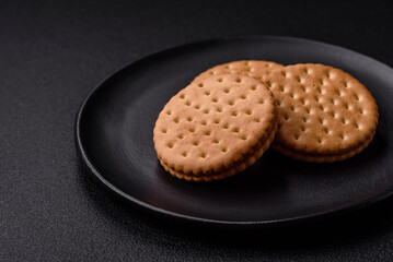 Round dotted snack snack cookies with cream on a dark concrete background