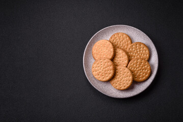 Round dotted snack snack cookies with cream on a dark concrete background