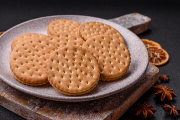 Round dotted snack snack cookies with cream on a dark concrete background