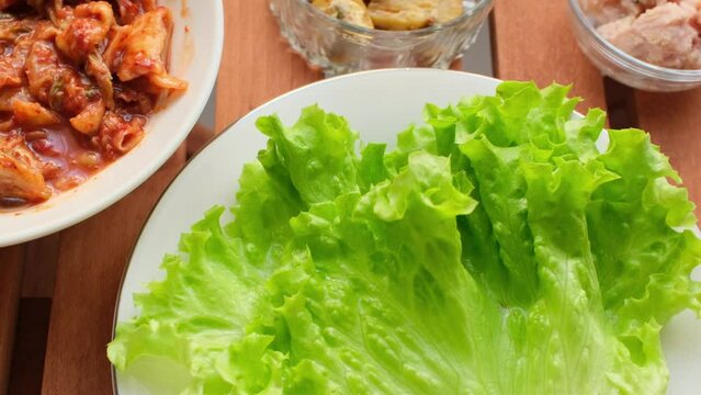 raising with various crops at the restaurant table, wrapping mushrooms and kimchee in cabbage