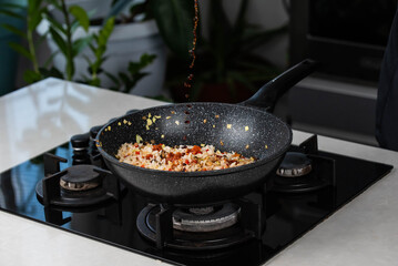 Close up of Chef cook hands cooking roasted vegetables with rice for Asian cuisine in frying wok pan on gas stove.