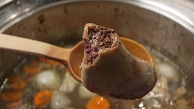 Delicious bone broth with carrots and spices and internal structure of chopped bone