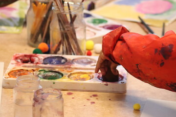 Children paint, paint, brushes and paper holding the children's hands.