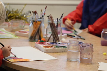 Children paint, paint, brushes and paper holding the children's hands.