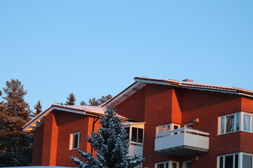Brick house in a residential area in Östersund. Winter with a lot of snow after snowfall on footpaths and in the parking lot. Pine trees near houses with snow on the twigs. Winter in Östersund.

