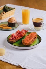 Spanish breakfast, two sandwiches with grated tomato and salted thinly sliced pork, orange juice, coffee with condensed milk and a muffin. Table setting. Breakfasts of the peoples of the world. 