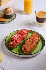 Spanish breakfast, two sandwiches with grated tomato and salted thinly sliced pork, orange juice, coffee with condensed milk and a muffin. Table setting. Breakfasts of the peoples of the world. 
