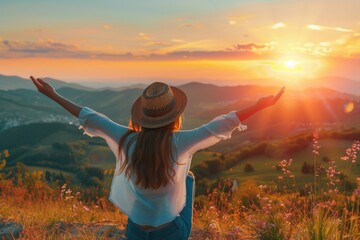 A woman with arms outstretched, enjoying a beautiful sunset in the mountains.