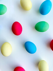 Colorful Easter eggs scattered on white background, flat lay composition for spring holiday celebration and decoration ideas. For Easter holiday promotions, themed party invitations, seasonal blog