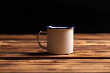 Mug with smoke, white coffee mug on rustic wood releasing smoke, dark background, selective focus.