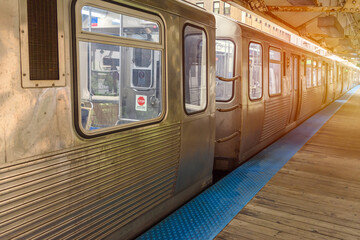 Silver commuter light train stationary at an eleveted station  in downtown Chicago