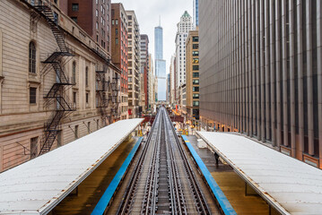 Elevated train station and tracks of Chicago rapdit transit system running between high rise buildings in downtown on a cloudy spring day