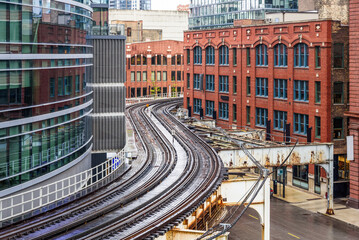 Curving elevated rail tracks between both tradtional and modern buildigs in downtown Chicago on a raining spring day