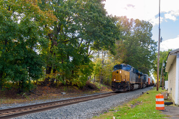 Powerful diesel locomotive pulling a freight train loaded with containers on a sunny autumn morning