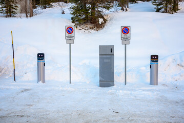 Charging station for electric cars in a snowy parking lot at a ski resort in the Alps in winter