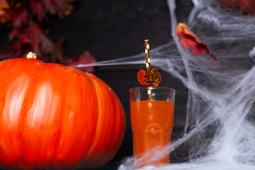 A glass of juice with a pumpkin and a spider web for Halloween