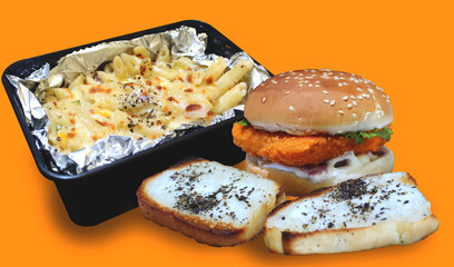Fast food on a wooden table including white sauce pasta with burger and garlic white cheese sprinkled roasted breads on orange background