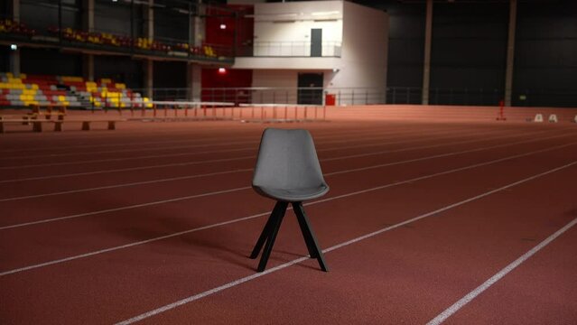 Turning lights on at the chair in the stadium. In the middle of the track and field stadium in a dark room with cinematic background. 10- bit. Camera zoom. Empty and moody stadium. 