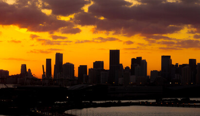 Panorama sunset silhouette of Miami downtown from South Beach with skyscrapers and cruise terminal against the orange sky of the setting sun 