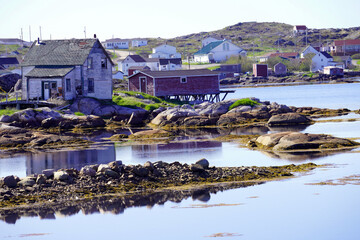 Fogo Island fishing village with reflection of buildings in the water on a summer day
