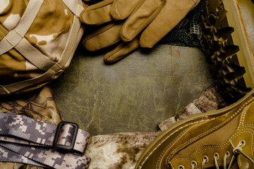 A pair of military gloves and a belt are neatly arranged on top of a khaki steel table, creating a...