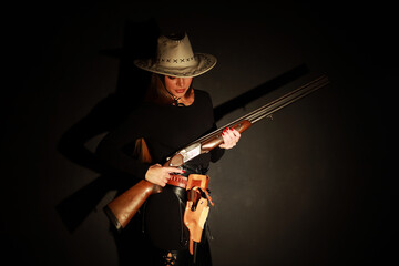 Beautiful young woman with shotgun and old revolver low key portrait
